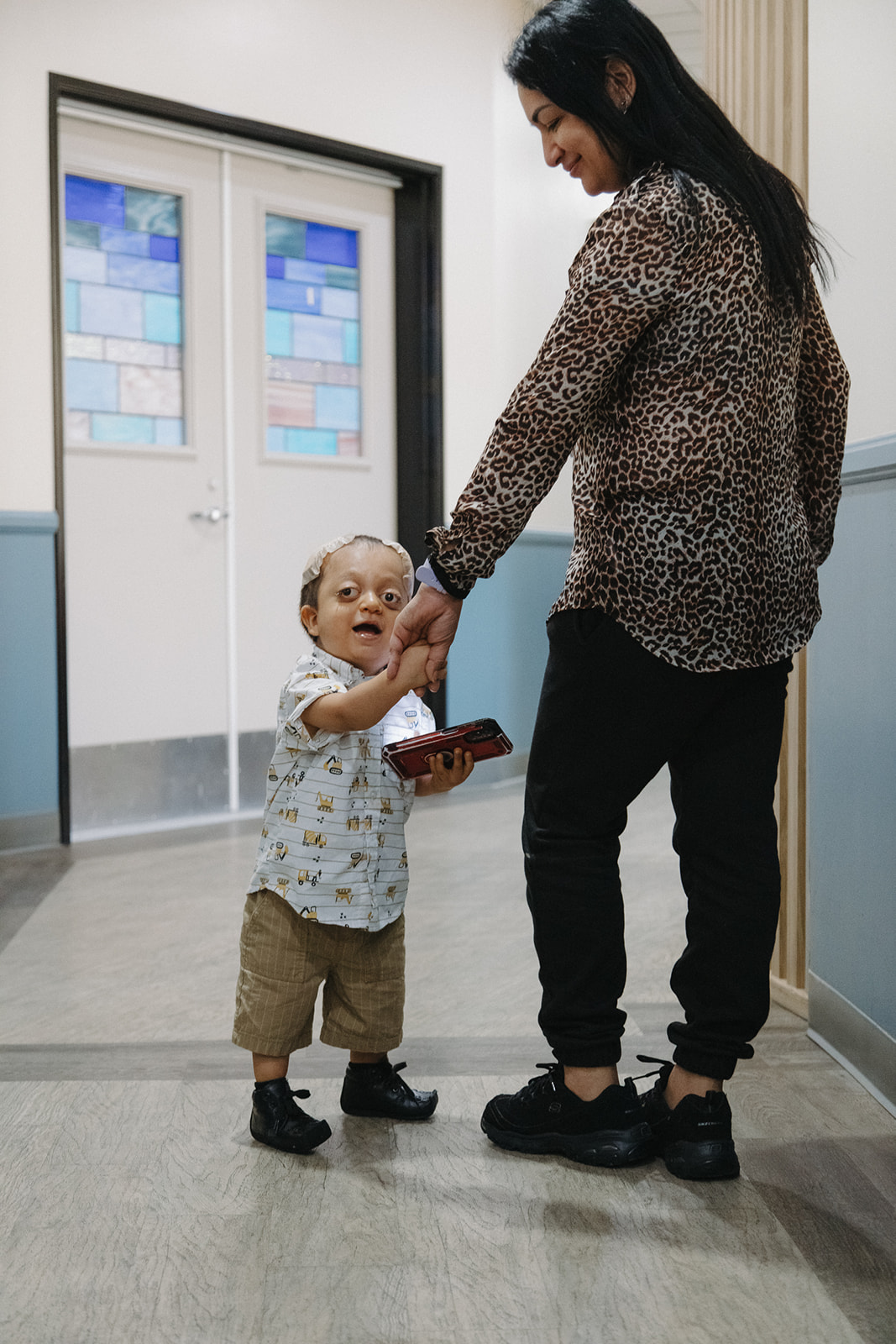 Boy and Mom holding hands walking down the hallway 