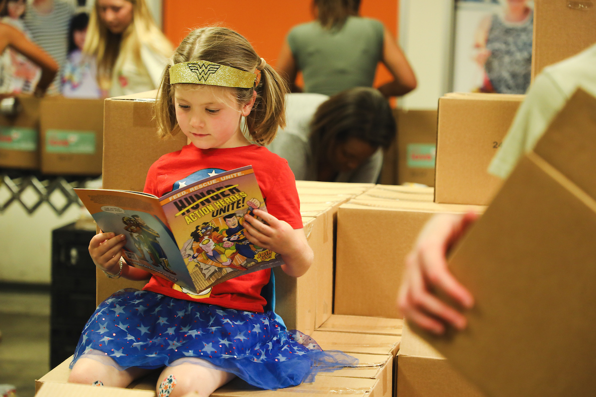 Girl in superwoman outfit reading a book