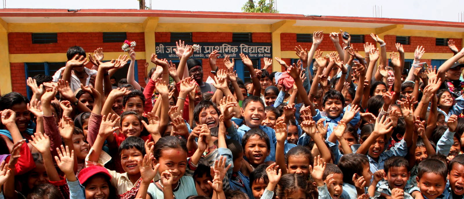Children celebrating outside a school, pictured on buildOn’s Nepal fundraising campaign