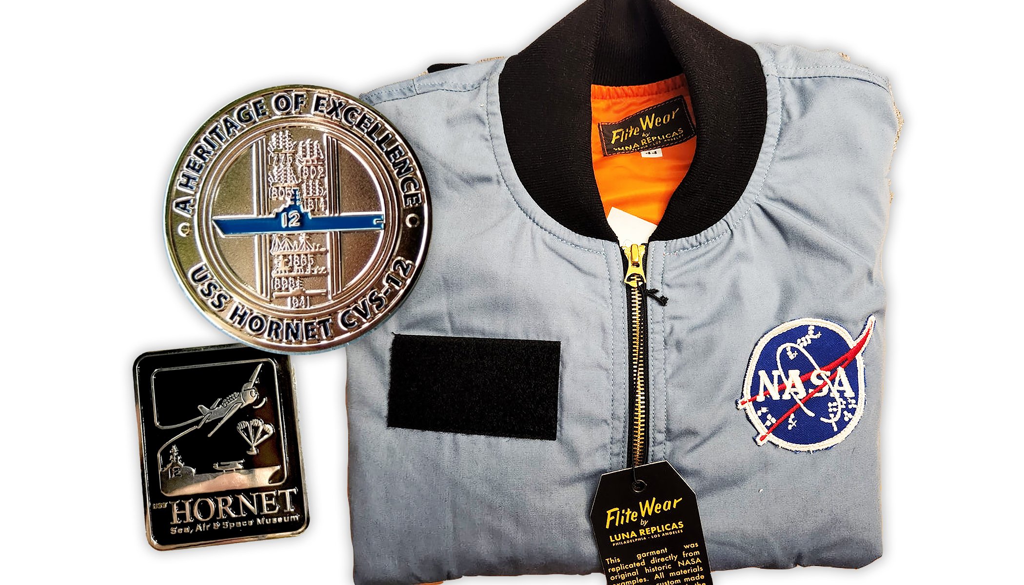 Hornet Museum logo pin, commemorative challenge coin, and NASA flight jacket.