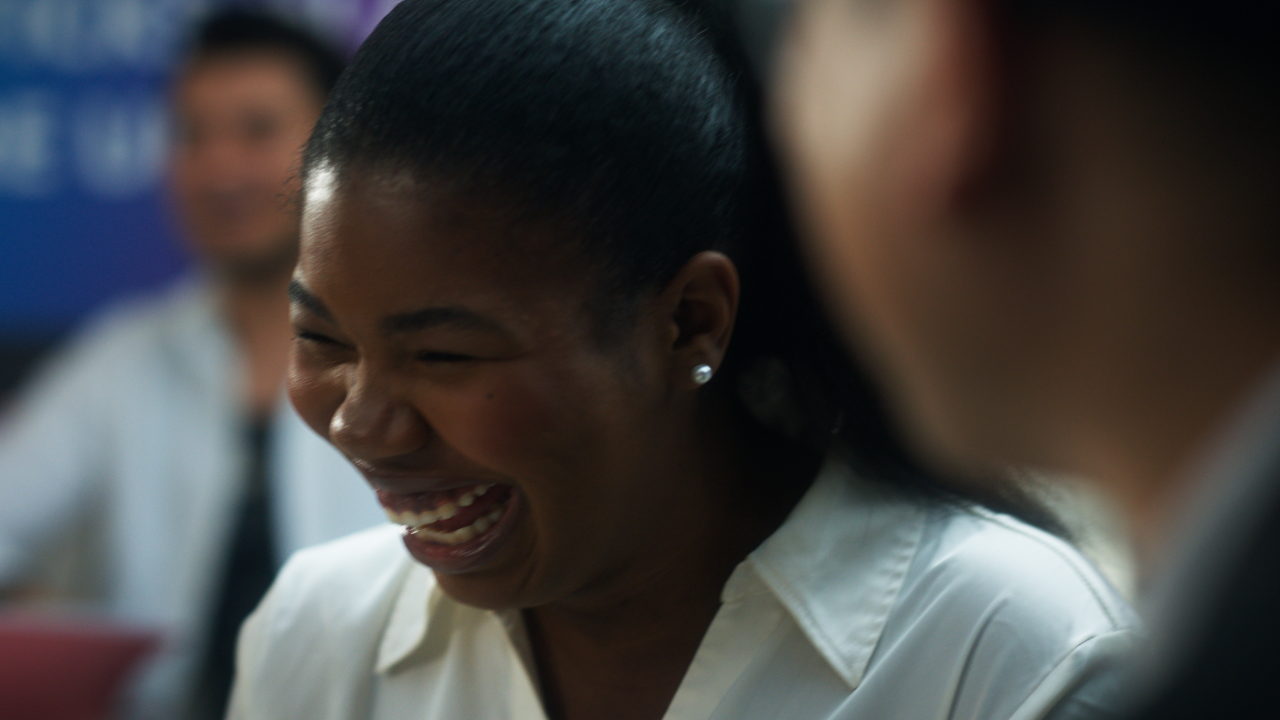 A teen girl smiling and laughing with a friend.