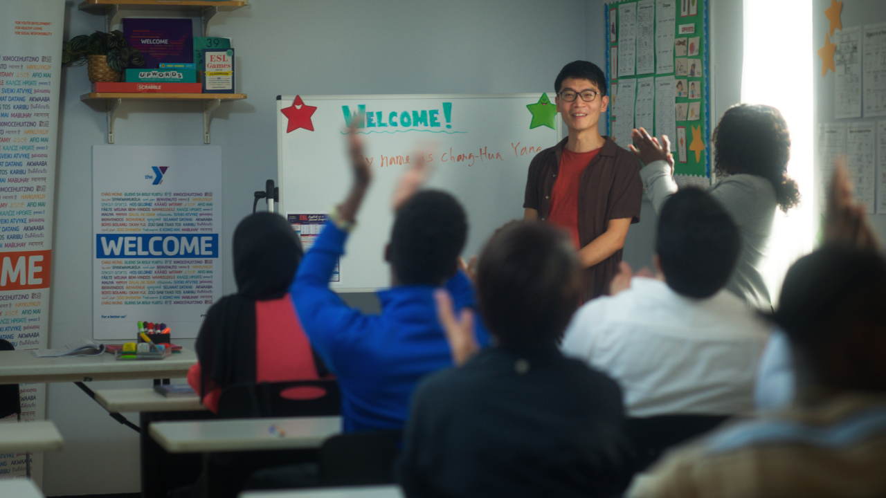 A young man teaching a classroom full of adult continuing education students.