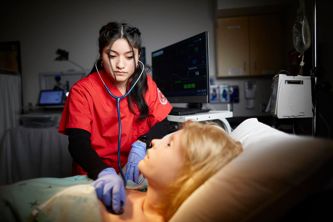 A nursing student practicing on an animatronic patient. 