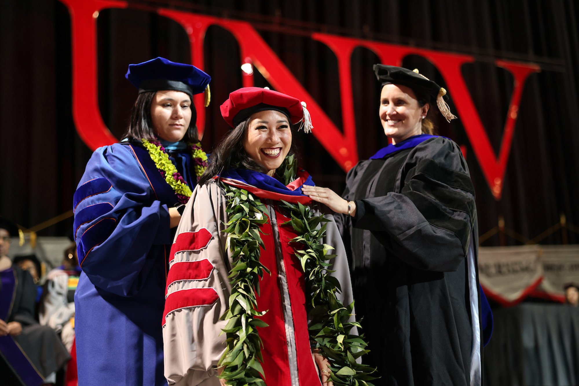 A Ph.D. student at commencement receiving their graduation hood. 