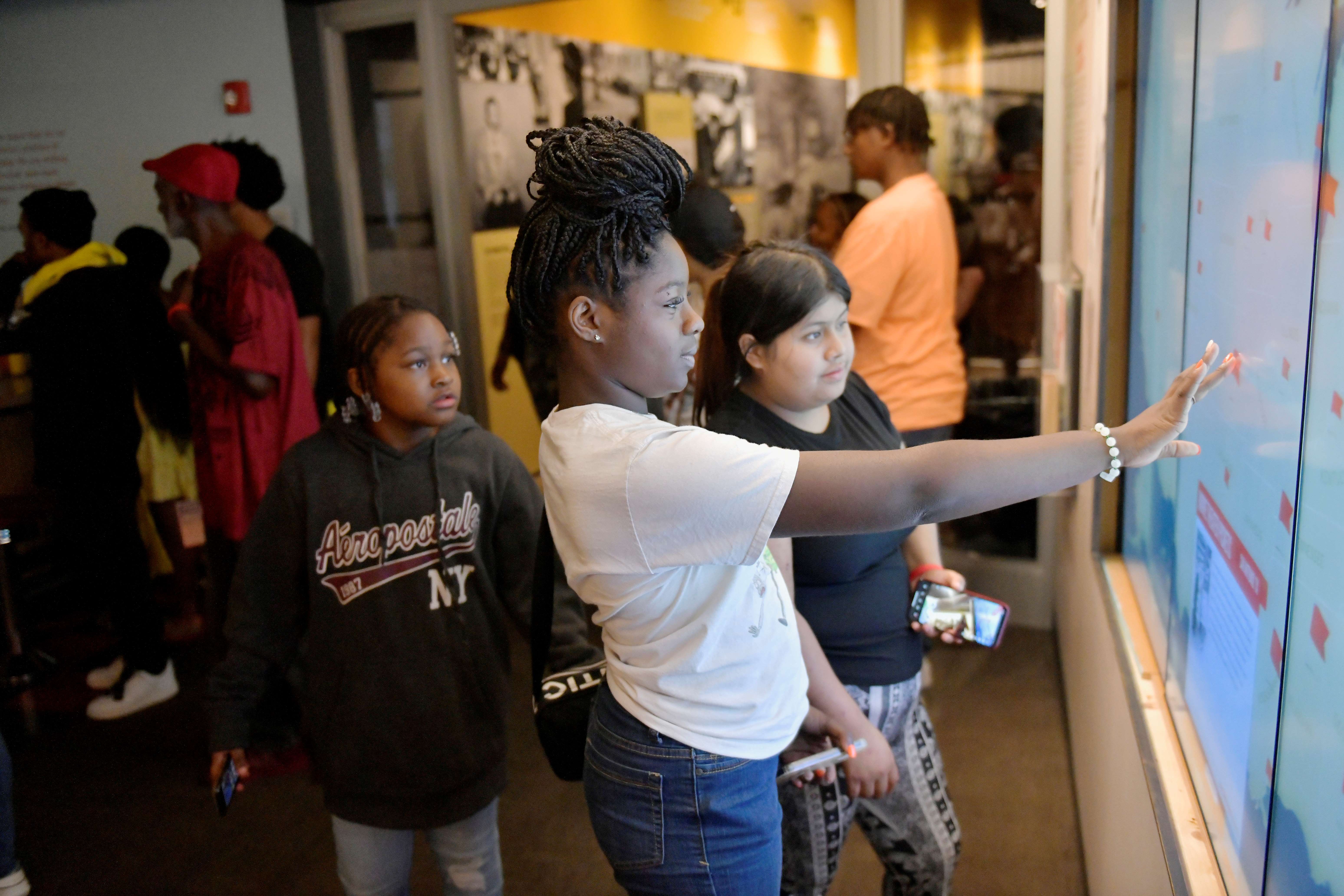 Young girl and fellow students interacting with a digital exhibit in the Museum