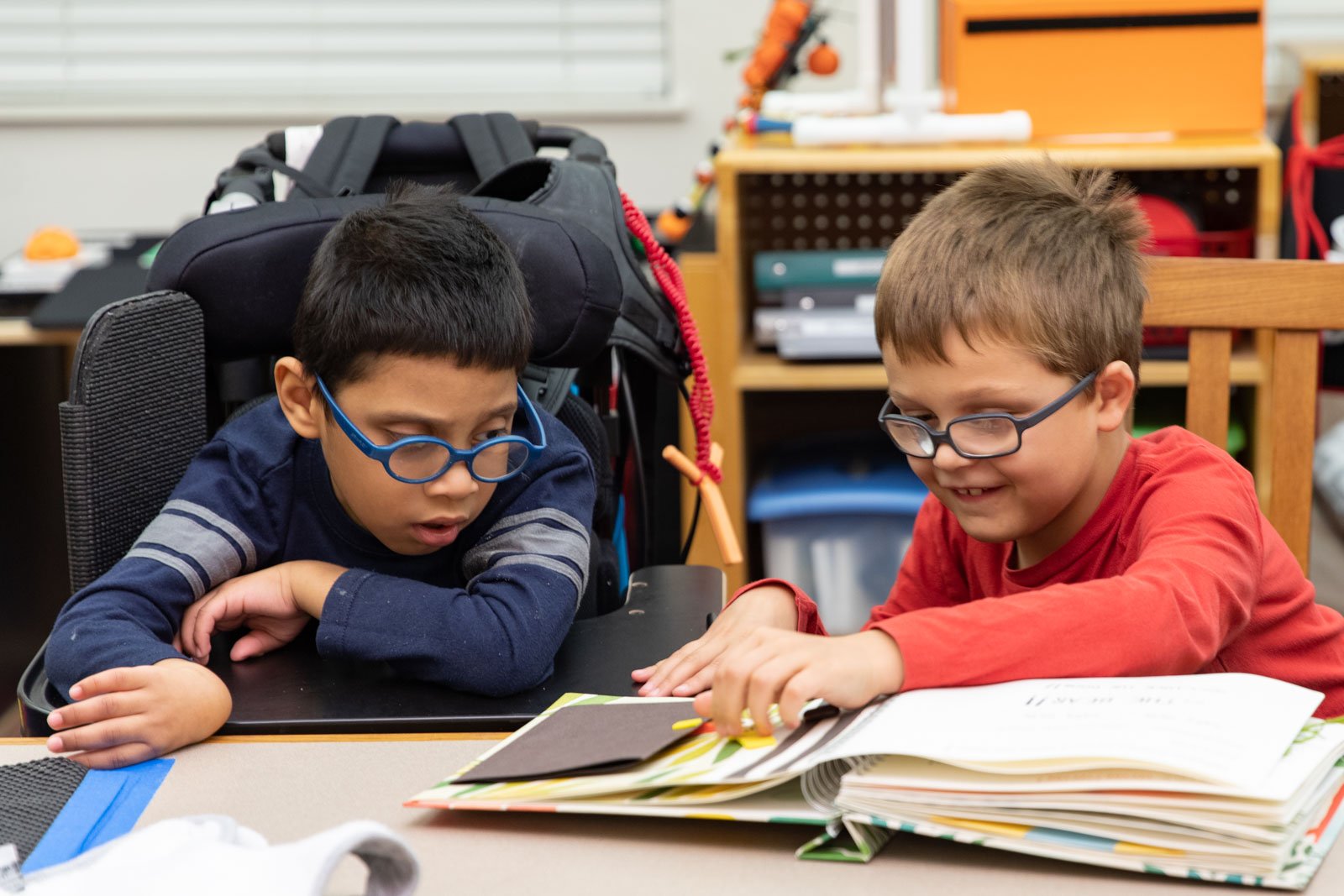 Two kids with classes look at books