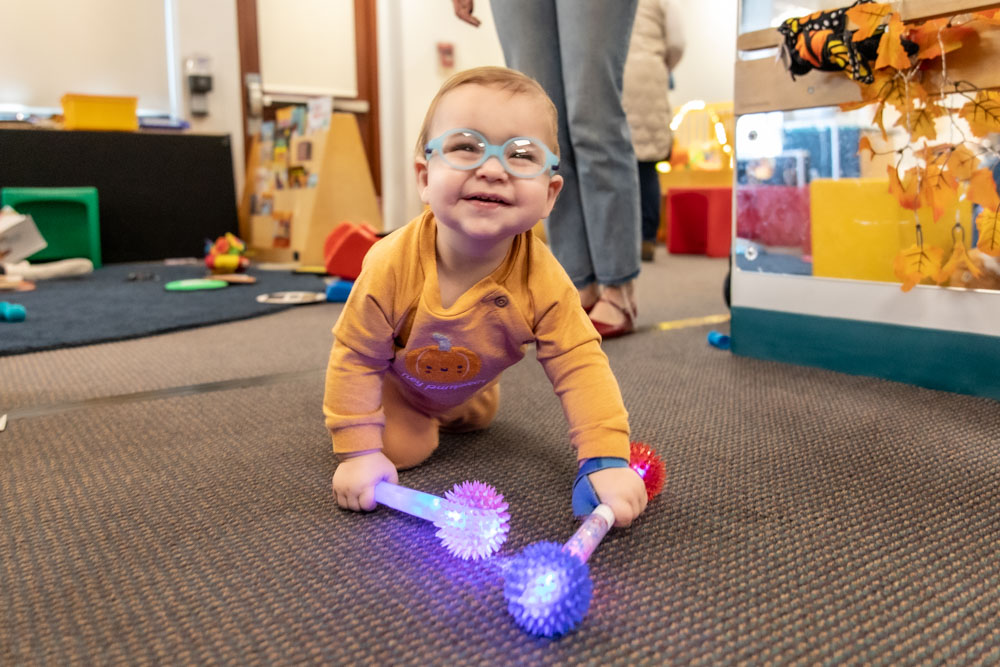 A child smiles with classes and playing with toys
