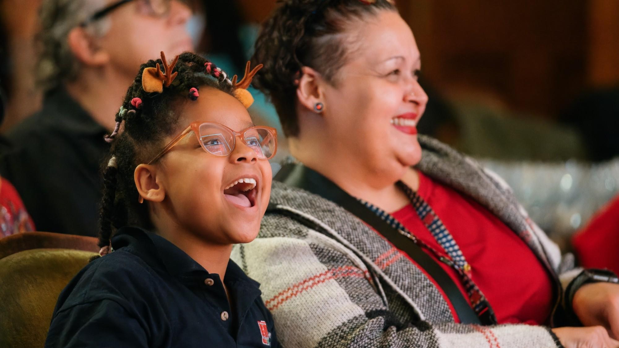 A mom and daughter laugh and smile while watching a musical production at the Abrons Arts Center.
