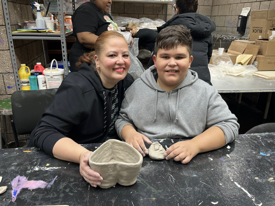 A mother and son show off their ceramics creations in an Abrons art studio.