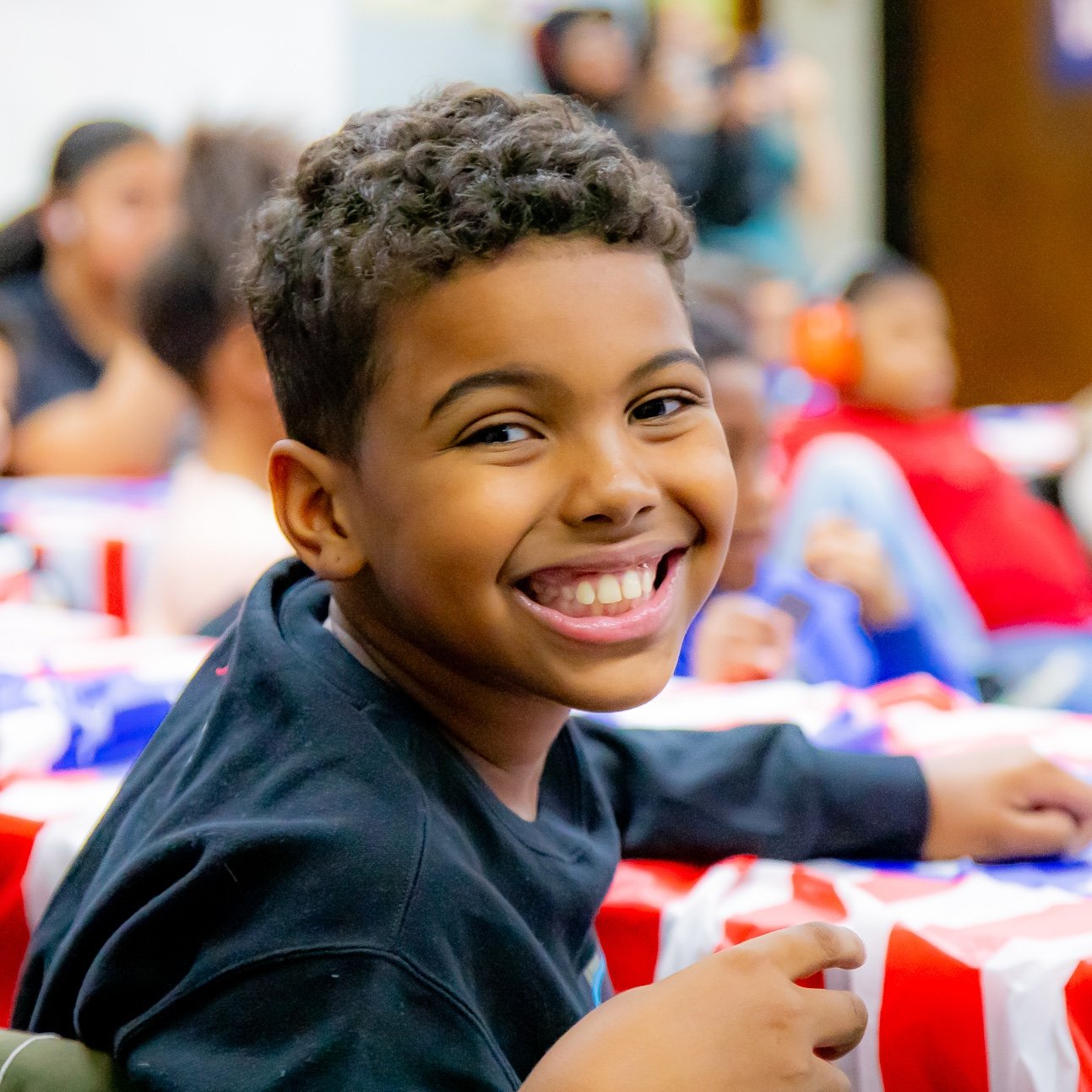 An elementary school-aged child smiling during an afterschool civics lesson.