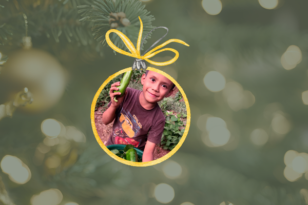 An image of a Christmas ornament featuring a boy holding cucumbers he has picked. 