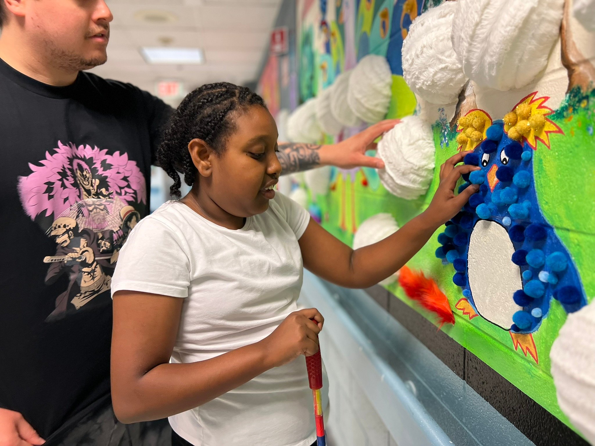A young black girl interacts with art in the Children's Development Center, which includes tactile animals and large Braille writing.