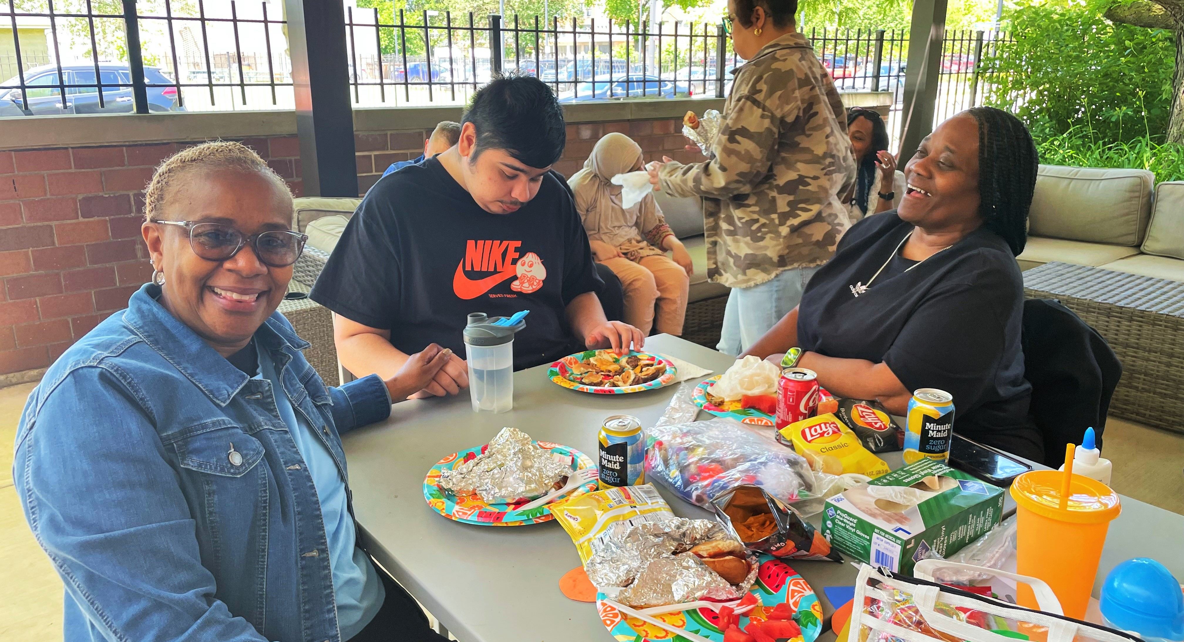 A high school student from our Children's Development Center enjoys lunch with school paraprofessionals on The Lighthouse's patio.