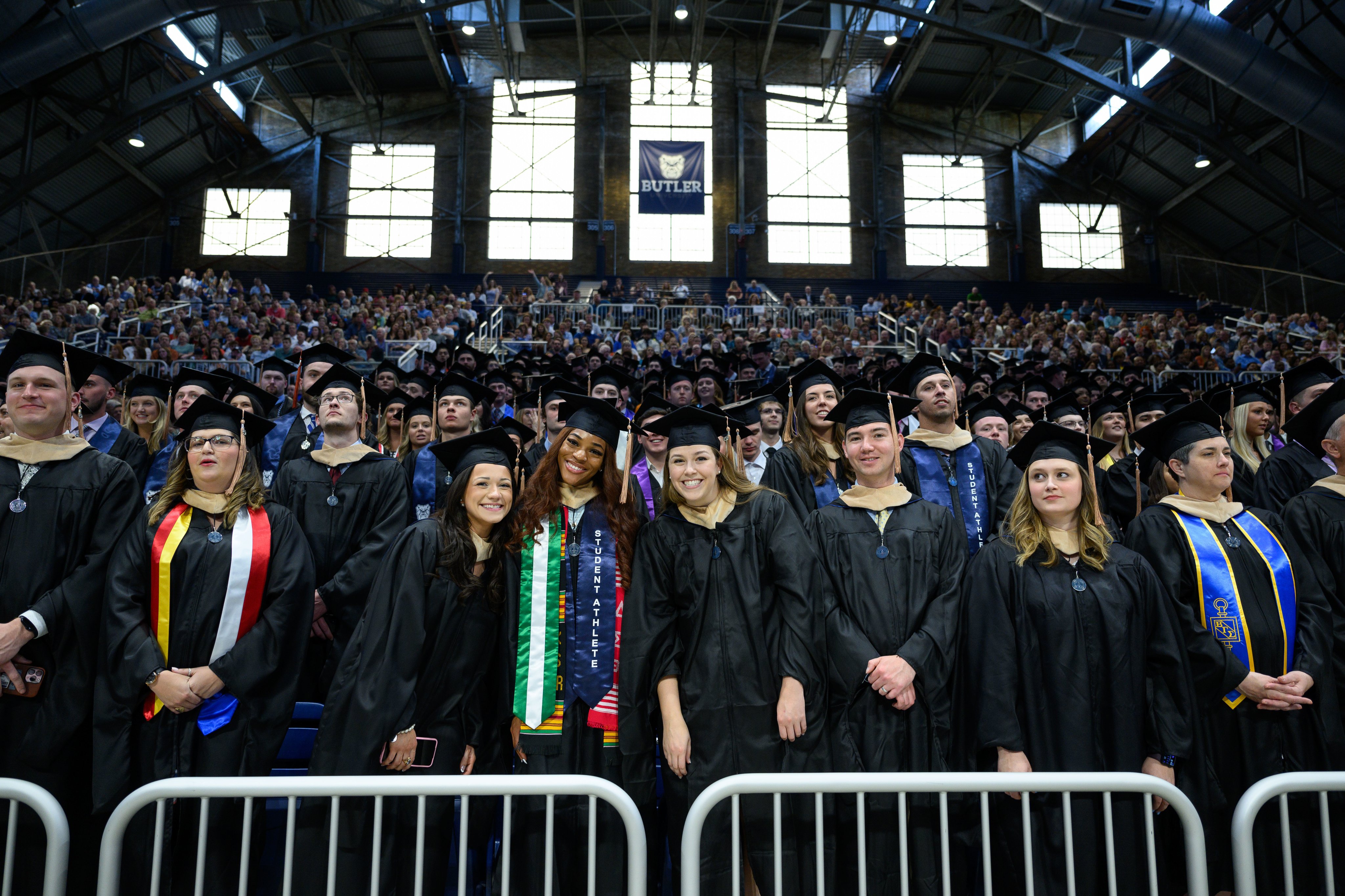 Butler students smile towards the camera, dressed in caps and gowns for commencement ceremonies.