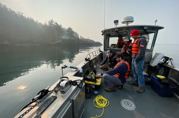 Members of the Seattle Aquarium conservation research team on a boat conducting kelp research using a remotely operated vehicle.