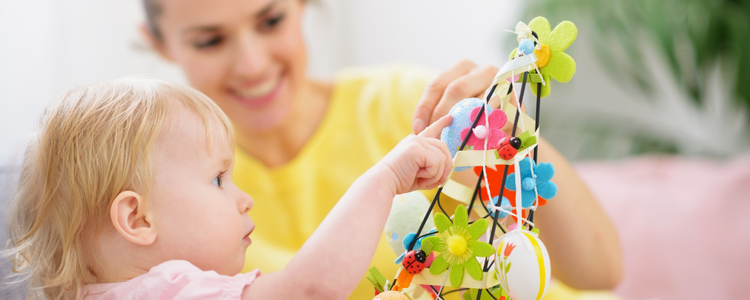 Baby playing with toy with teacher in background