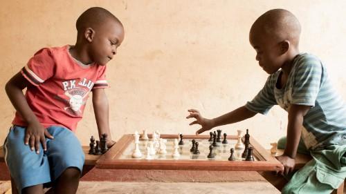 Two young boys play chess.