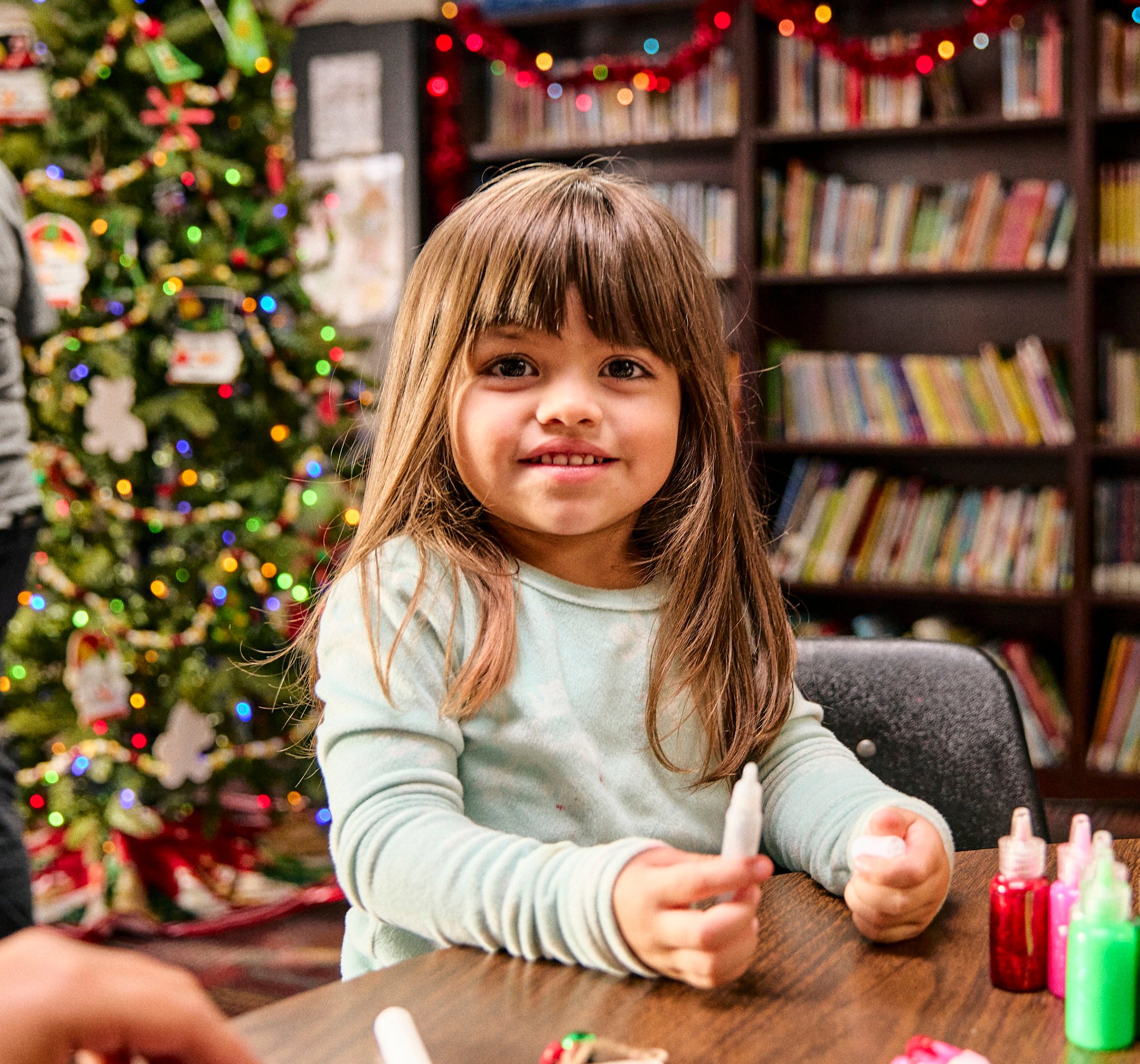 Girl with crafts in front of Christmas tree
