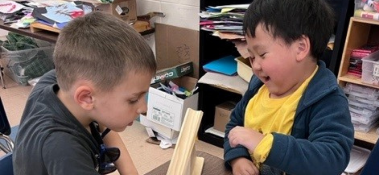 two young boys laughing at their rolling marble activity