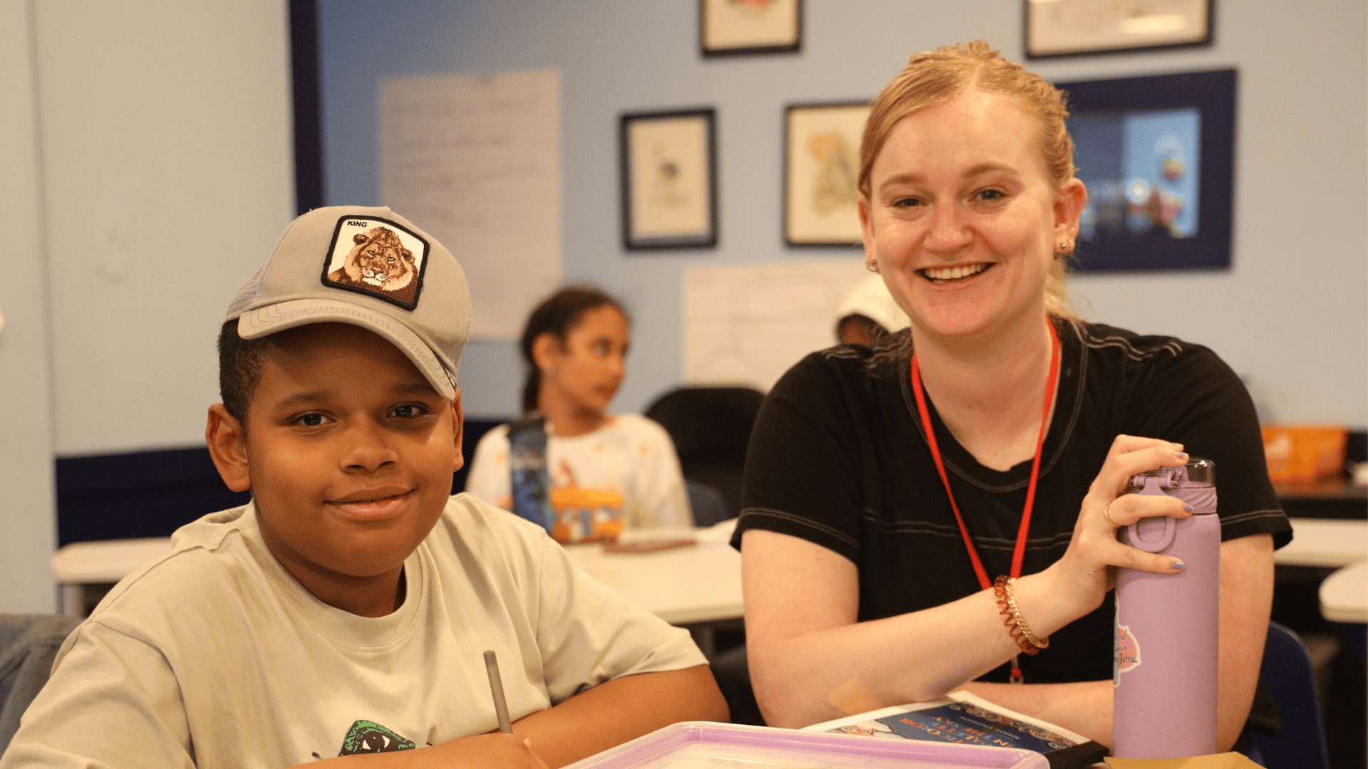 An 826NYC student wearing a hat and volunteer are smiling, facing the camera.
