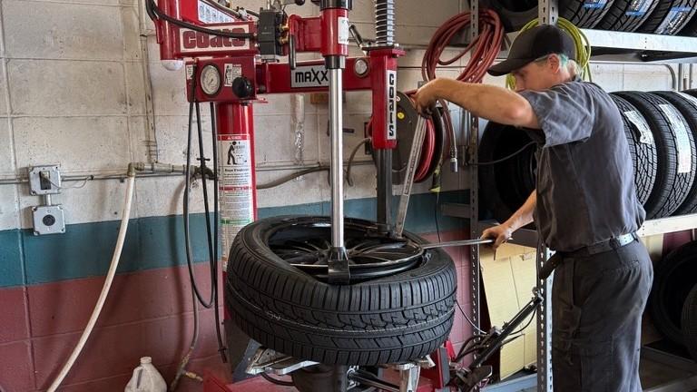 A technician at The Lift operating the tire changing machine, one of the steps that goes into replacing and balancing tires on a vehicle.