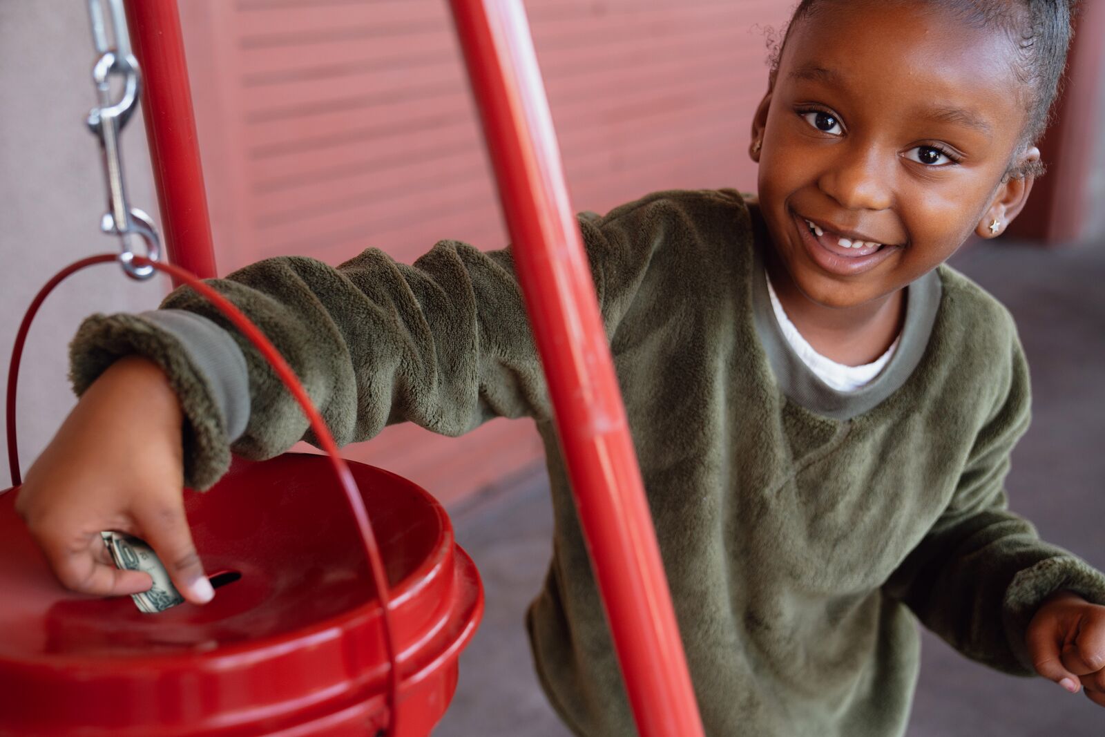 A young girl donating to a Salvation Army kettle.