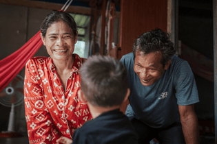 A boy from LWB's Safe Haven Foster Care Program is facing away from the camera, looking at his beaming foster parents.