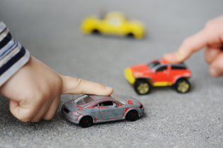 Little hands are playing with toy cars.