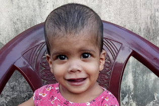 A young girl in LWB's India Medical Program sits on a chair and smiles at the camera.