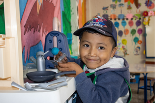 Young boy playing in the toy kitchen.