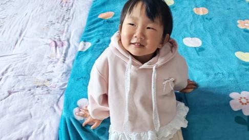 Amanda is wearing a pink hoodie with a white lace frill around the bottom.  She looks off to the left.