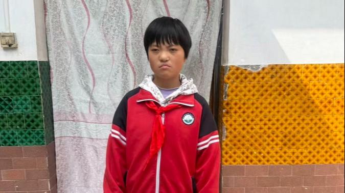 Lonnie looks onward unsmiling.  She is wearing a read jacket with white stripes on the sleeves and a red school scarf.