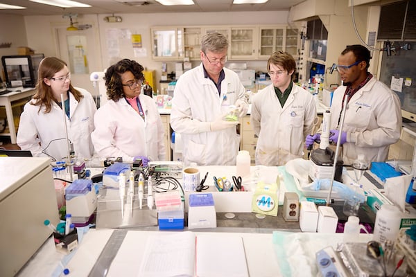 A professor working with students in a lab