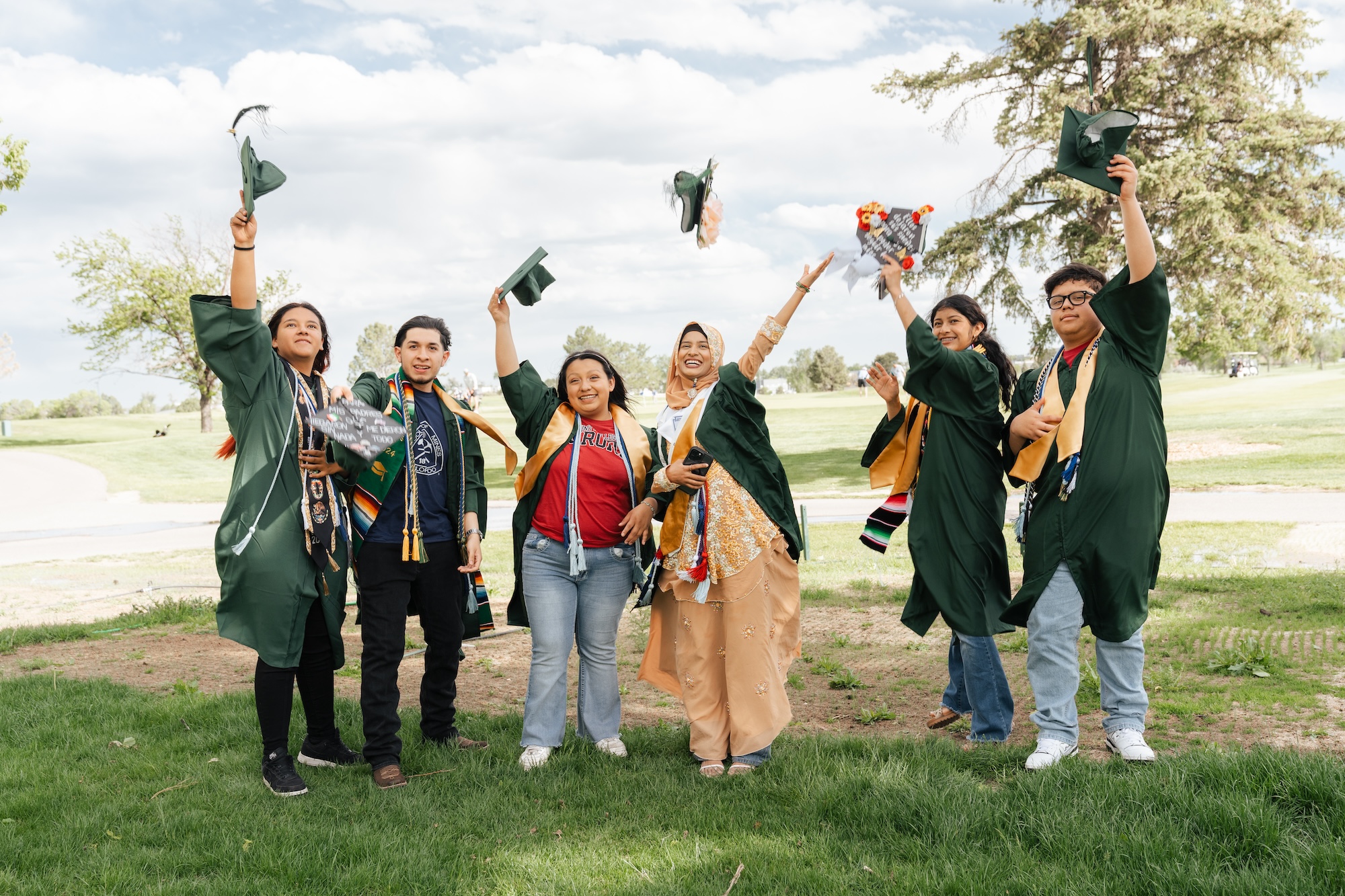 colorado senior in high school graduates throwing their caps in a graduation success picture