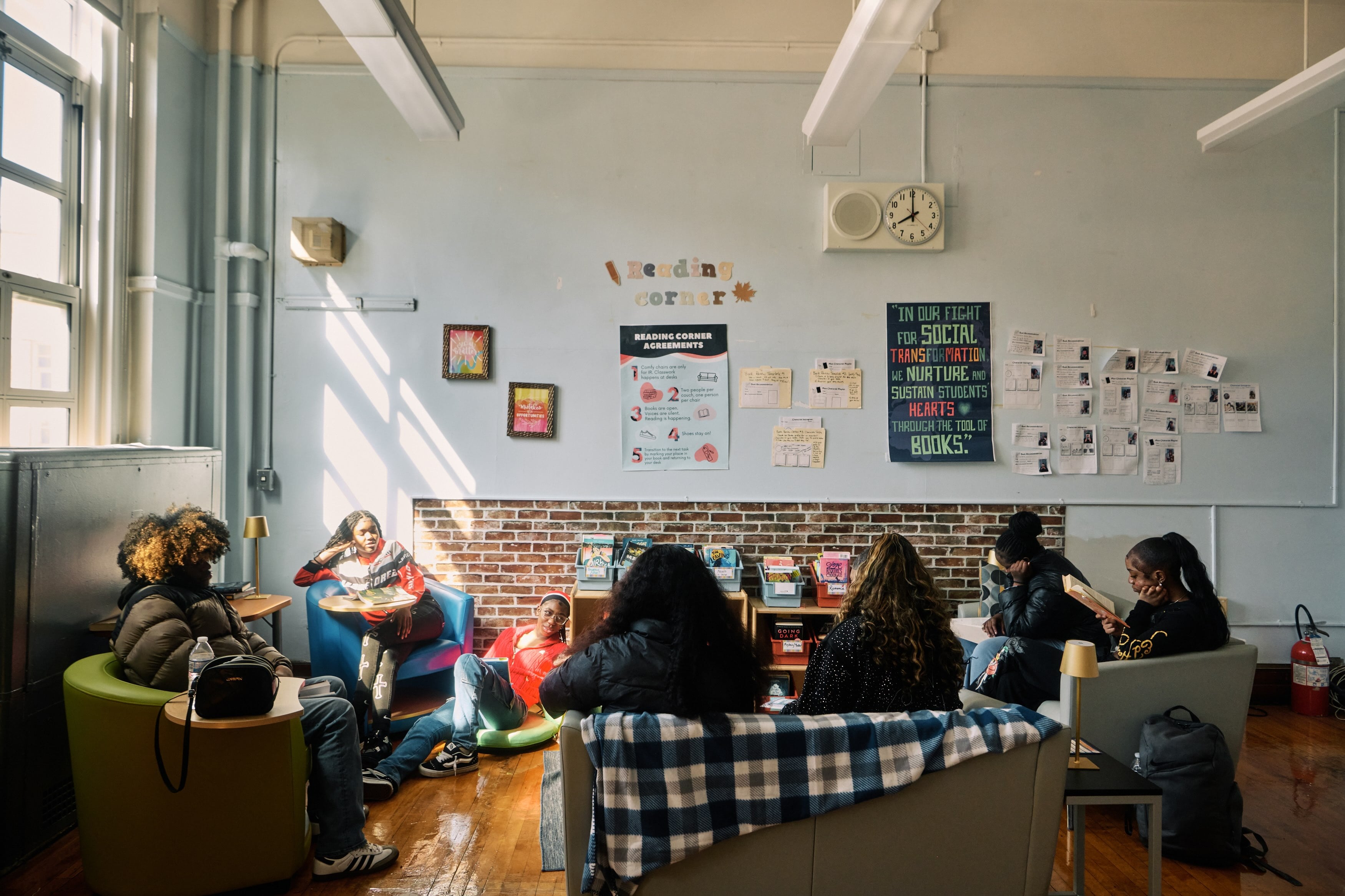 A group of students gathered around a room reading books.