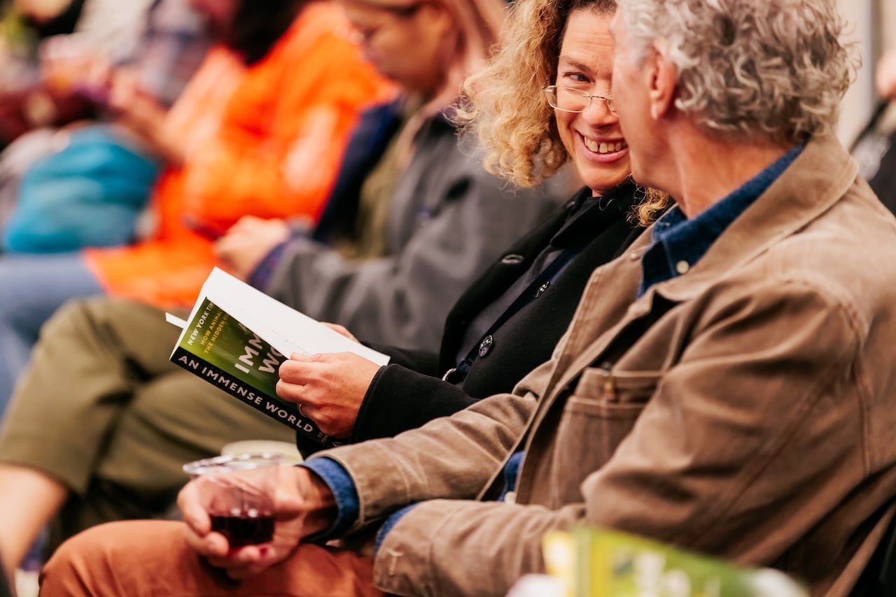 Two adults conversing in the audience of an author book talk.