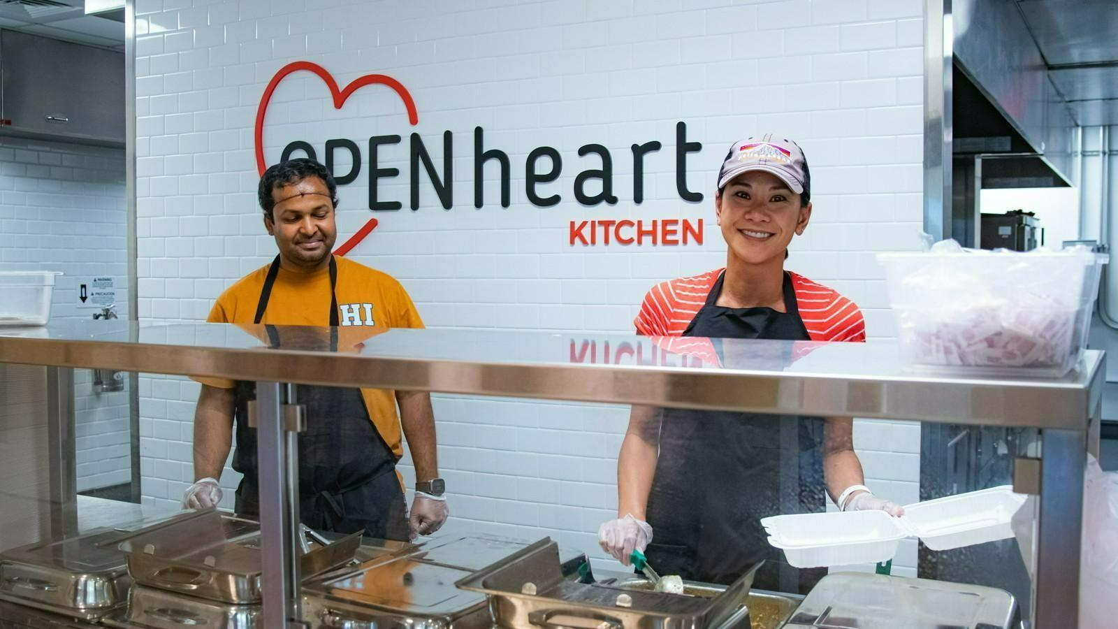 Two Open Heart Kitchen volunteers serving a meal